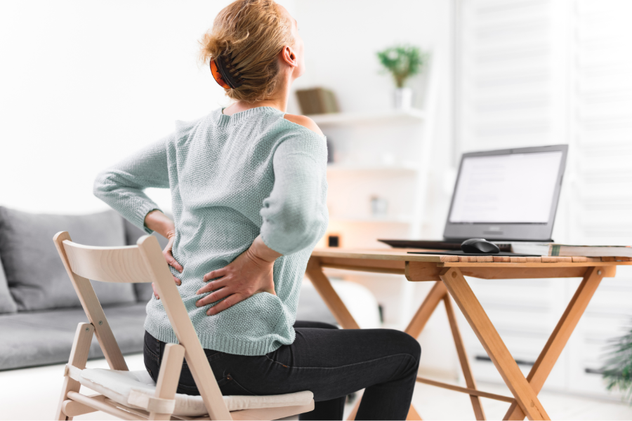 person at desk with laptop hoding lower back and hip in pain