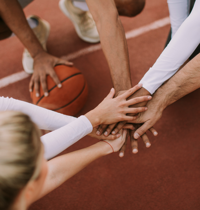 diverse caual adult basketball team stack hands befor breaking huddle