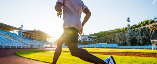 Man running on racetrack in stadium