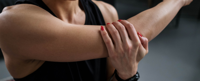 woman stretching harm with hand on elbow