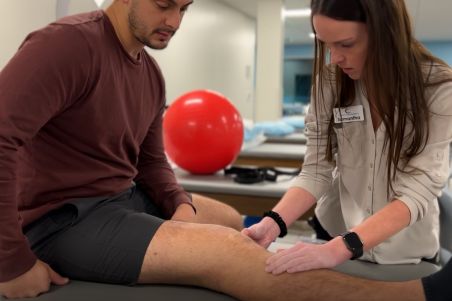 physical therapist examing patient leg and knee