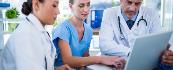 medical professionals huddeld in front of laptop