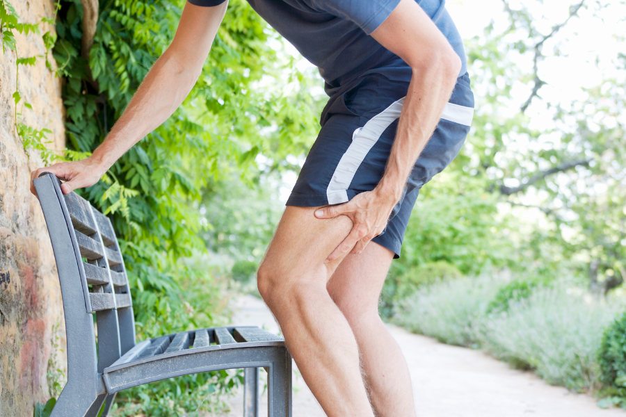 man at park outside hold thigh in pain