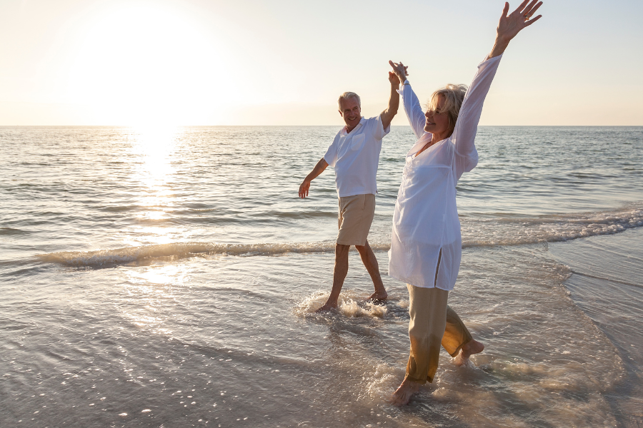 senior couple at the beach walking in the water at the shore