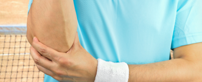 man on tennis court holding elbow in pain