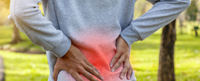 man grabbing lower back glowing red to indicate pain or discomfort