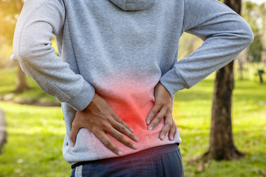 man grabbing lower back glowing red to indicate pain or discomfort