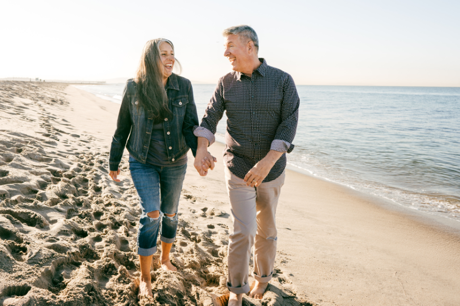 senior couple on beach walking on sand near the shore holding hands